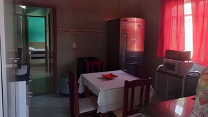 A compact room with a kitchenette, a dining table, and a single chair. - Oceana Suites Praia do saco (Mangaratiba)