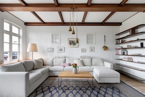 A modern living room with a sectional sofa, a coffee table, and a bookshelf.