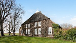 Una casa grande cubierta de hiedra, con un techo empinado y varias ventanas.