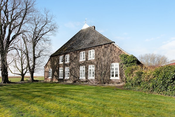 A large, ivy-covered house with a steep roof and multiple windows.