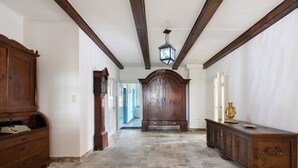 Un pasillo con piso de madera, un mueble grande de madera y un farol colgante.
