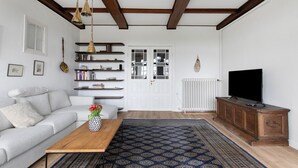 Una sala de estar con sofá, mesa de centro, televisor, aparador de madera, estanterías y una alfombra estampada.