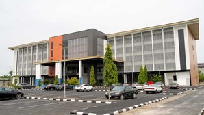 A modern building with a parking lot in front. - Julirose Hotel and Suites (Port Harcourt)