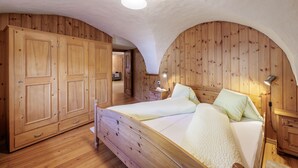 Ein Zimmer mit Holzboden, einem Bett, einem Kleiderschrank und einem Schreibtisch.