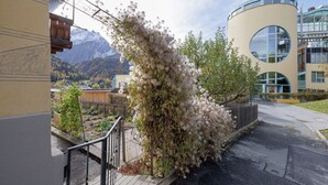 Ein modernes Gebäude mit einem Rundfenster und einem Balkon mit Blick auf eine gebirgige Landschaft.
