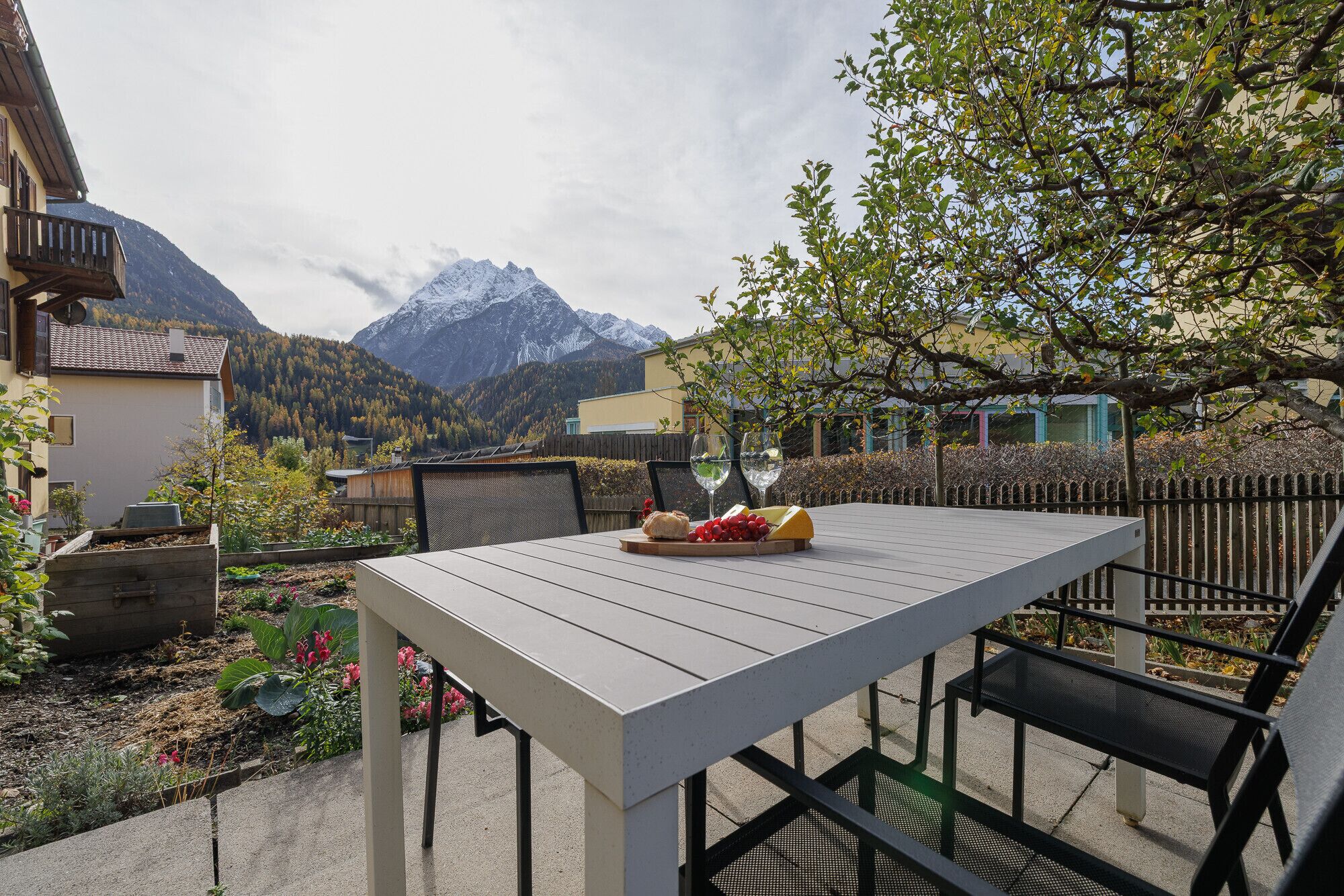 Una mesa con vistas a montañas, un jardín y un edificio.