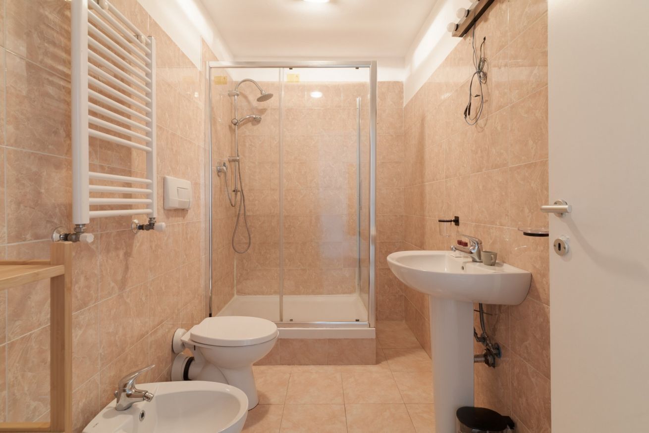 A modern bathroom with a shower, toilet, sink, and towel rack.