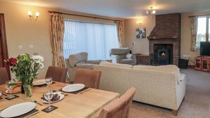 A dining area with a table set for four, a sofa, and a fireplace. - Pasture View (Whitby)