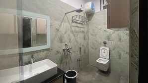 Un baño moderno con un espejo grande, un lavabo, un inodoro y una ducha.
