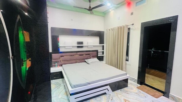 Un dormitorio con cama, mesitas de noche, ventilador de techo y ventana con cortinas.