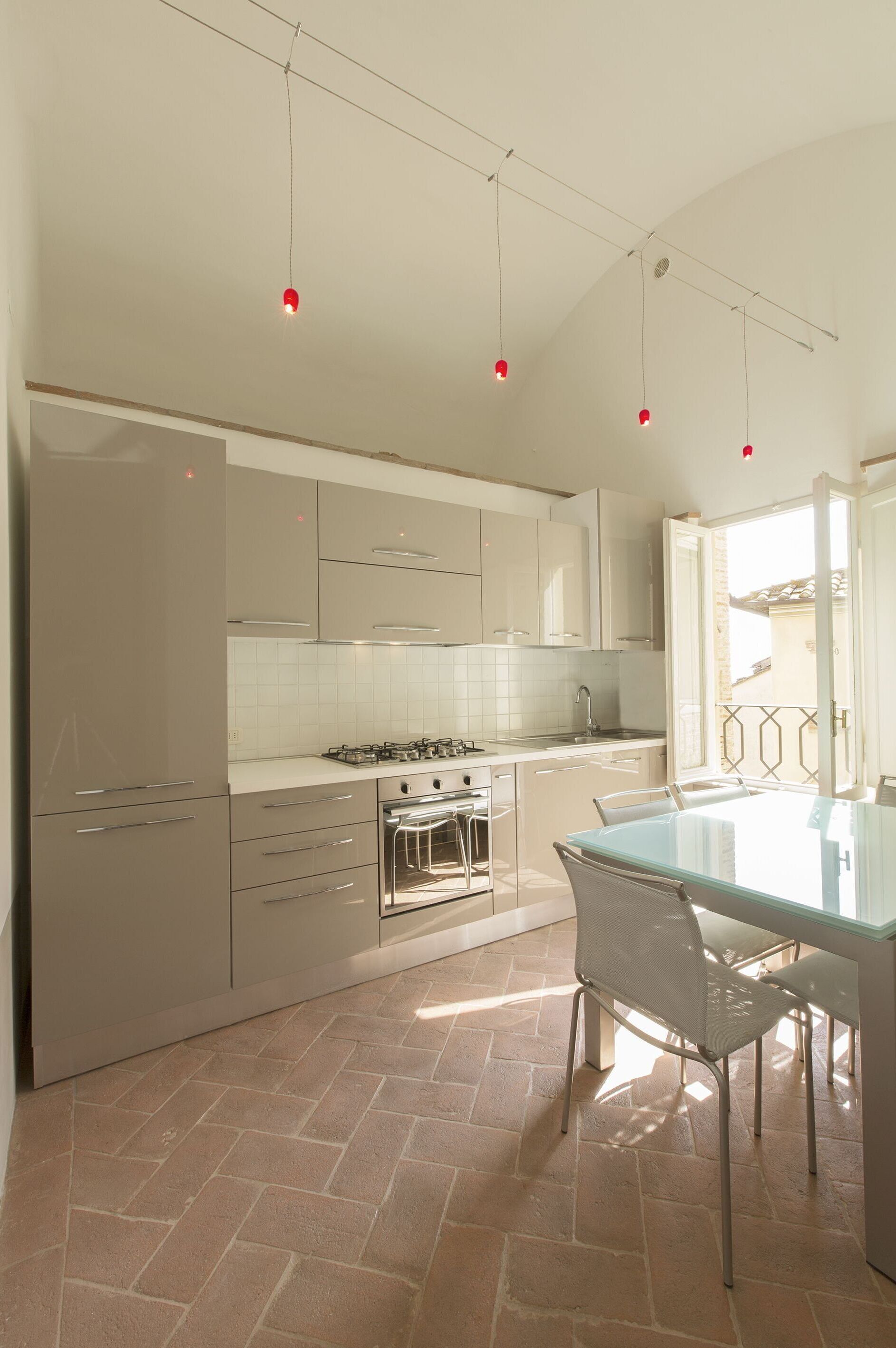 A modern kitchen with white cabinets, a gas stove, and a glass dining table.