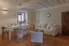 Uma área de refeições com uma mesa posta para quatro, um sofá branco e uma porta de madeira.
