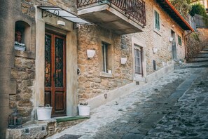 A narrow cobblestone street with stone buildings, a wooden door, and potted plants. - Casa San Valentino (Cortona)