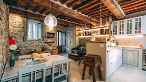 Una cucina rustica con pareti in pietra, travi in legno e un'area pranzo con tavolo e sedie.