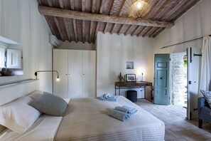 A bedroom with a large bed, a desk, and a wardrobe. - Tenuta Pomona (Cortona)