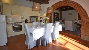 A dining area with a brick archway, white tablecloths, and chairs. - Casa i Pini (Cortona)