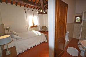 Ein Schlafzimmer mit Bett, Stuhl, Heizkörper und einem Fenster mit Vorhängen.