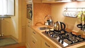 Une cuisine équipée d’une cuisinière à gaz, d’un évier, de placards et d’une fenêtre.