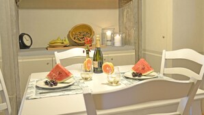 Une table à manger avec des assiettes de pastèque et de raisins, des verres de vin et une bouteille de champagne.