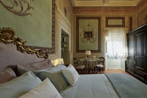 A hotel room with a large bed, a desk with chairs, a mirror, and a wardrobe. - Casa Ada e Sabo (Cortona)