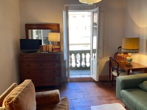A room with a wooden dresser, a television, a lamp, a green sofa, and a chair. - Appartamento La Piazzetta (Cortona)