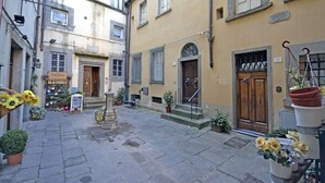 A narrow street with buildings, a wooden door, and potted plants. - Appartamento La Piazzetta (Cortona)