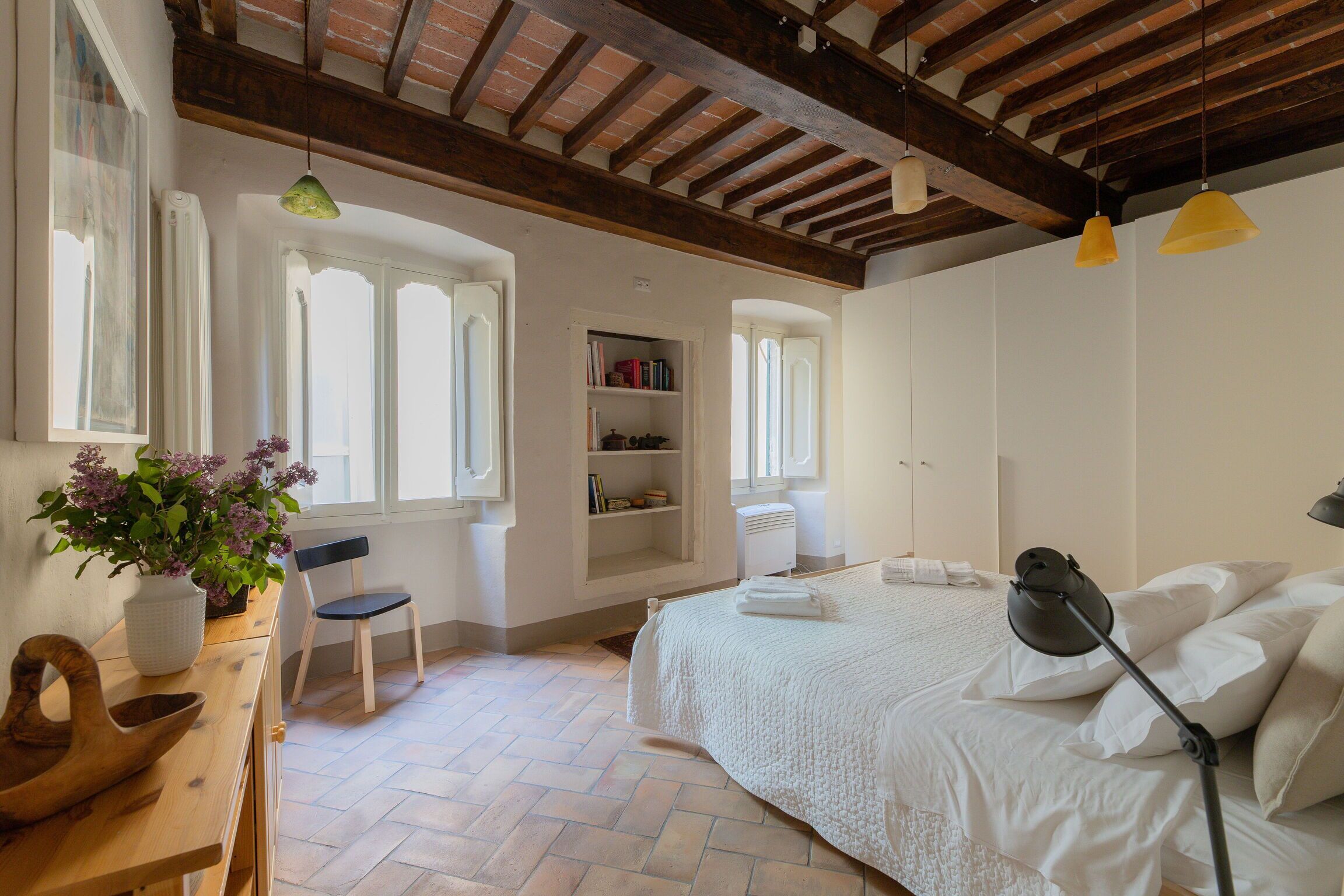 A bedroom with a bed, a desk with a chair, a bookshelf, and a window.