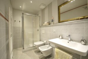 A modern bathroom with a glass shower enclosure, a bidet, a sink, and a mirror. - Appartamento Maccari (Cortona)