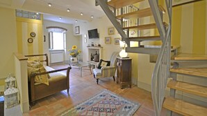 Ein geräumiges Wohnzimmer mit einer Holztreppe, einem Sofa, einem Sessel, einem Tisch und einer Lampe.