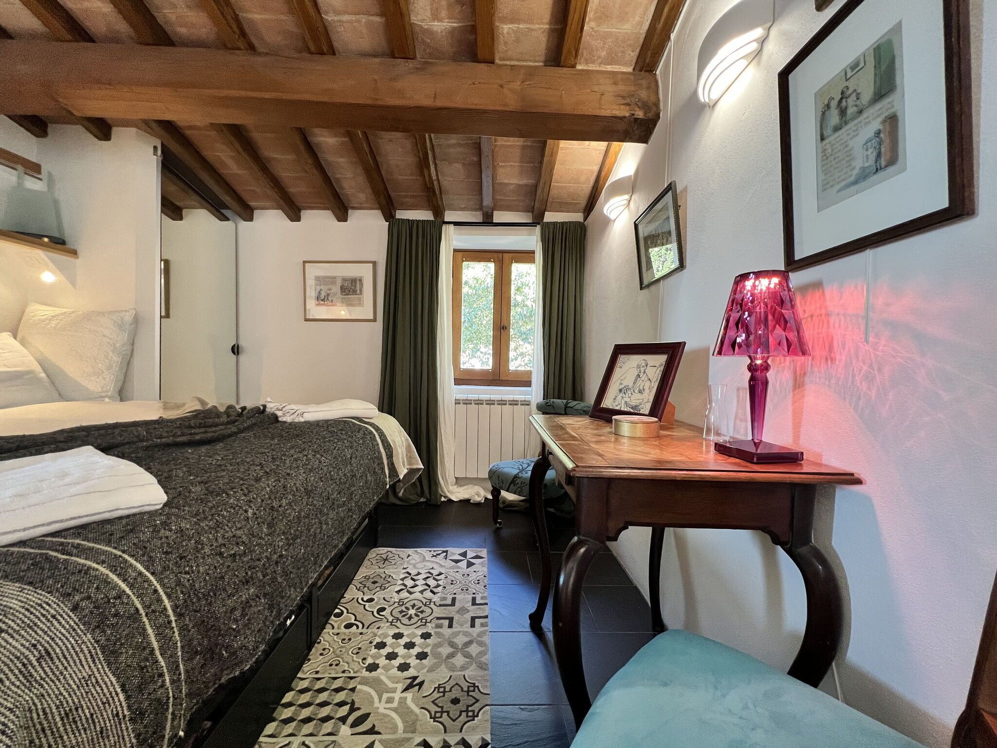 Une chambre confortable avec un lit, un bureau avec une lampe, une chaise et une fenêtre avec des rideaux.