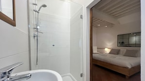 A modern bathroom with a glass shower enclosure, a white sink, and a wooden floor. - Vicolo Della Scala Rooms - Il Sole (Cortona)