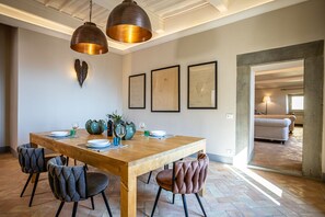 Zona pranzo con tavolo in legno, quattro sedie e due lampadari a sospensione.