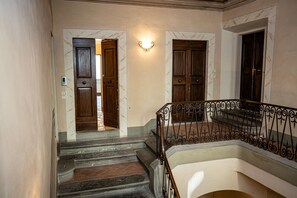 A staircase with a handrail and a wall-mounted light fixture. - Appartamento Vagnucci (Cortona)