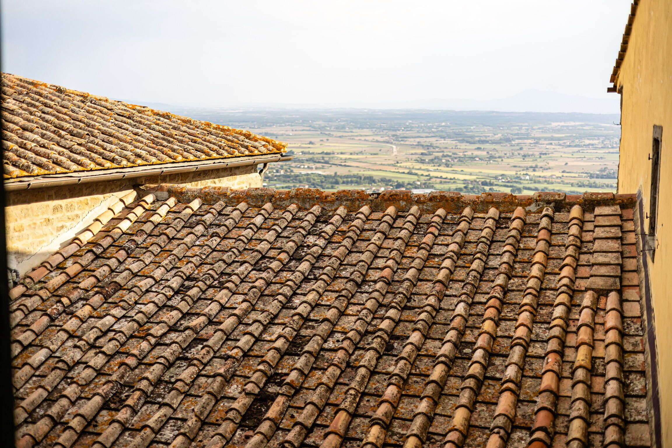 A rooftop with a tiled surface overlooking a rural landscape.