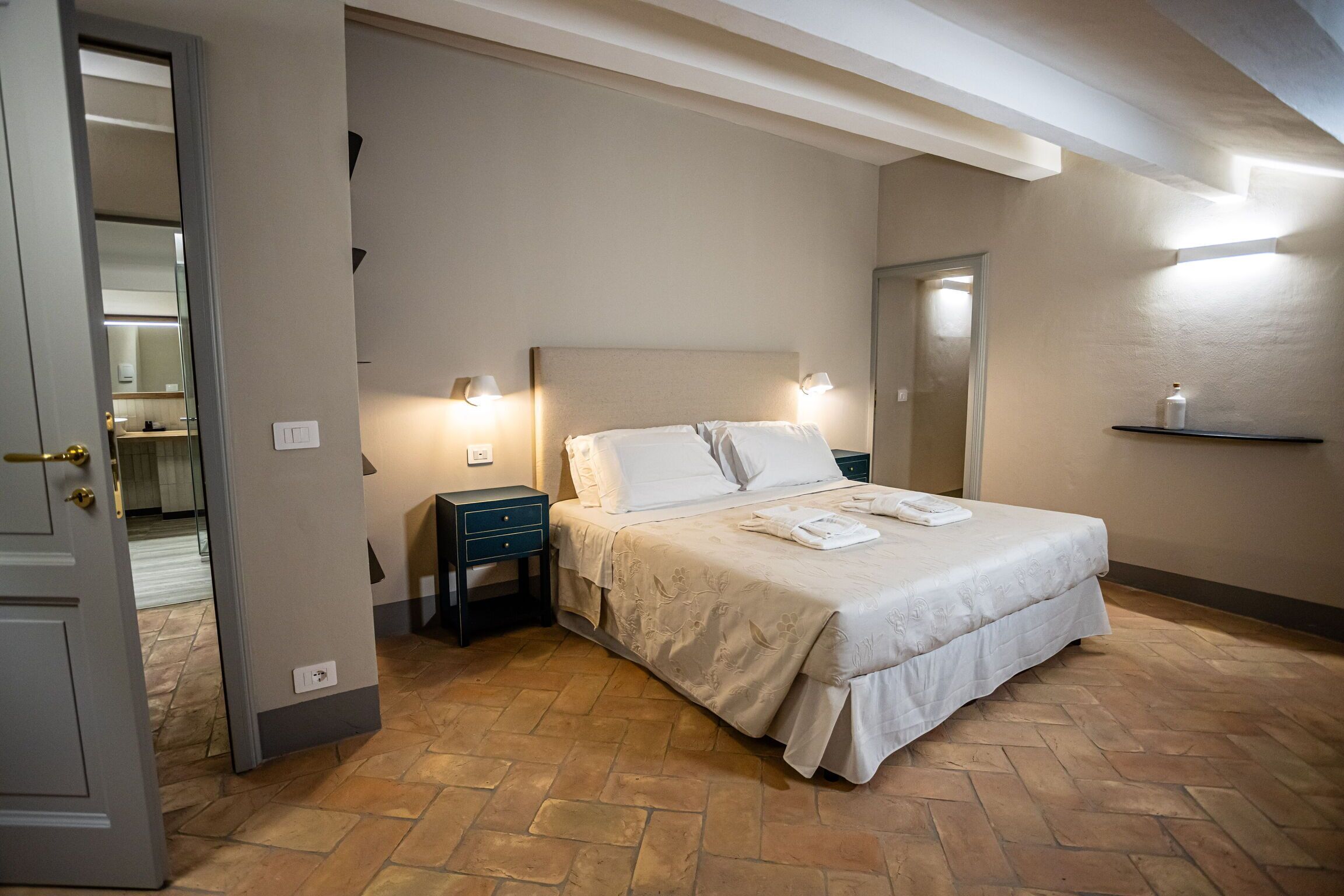 A bedroom with a bed, nightstands, and a mirror.