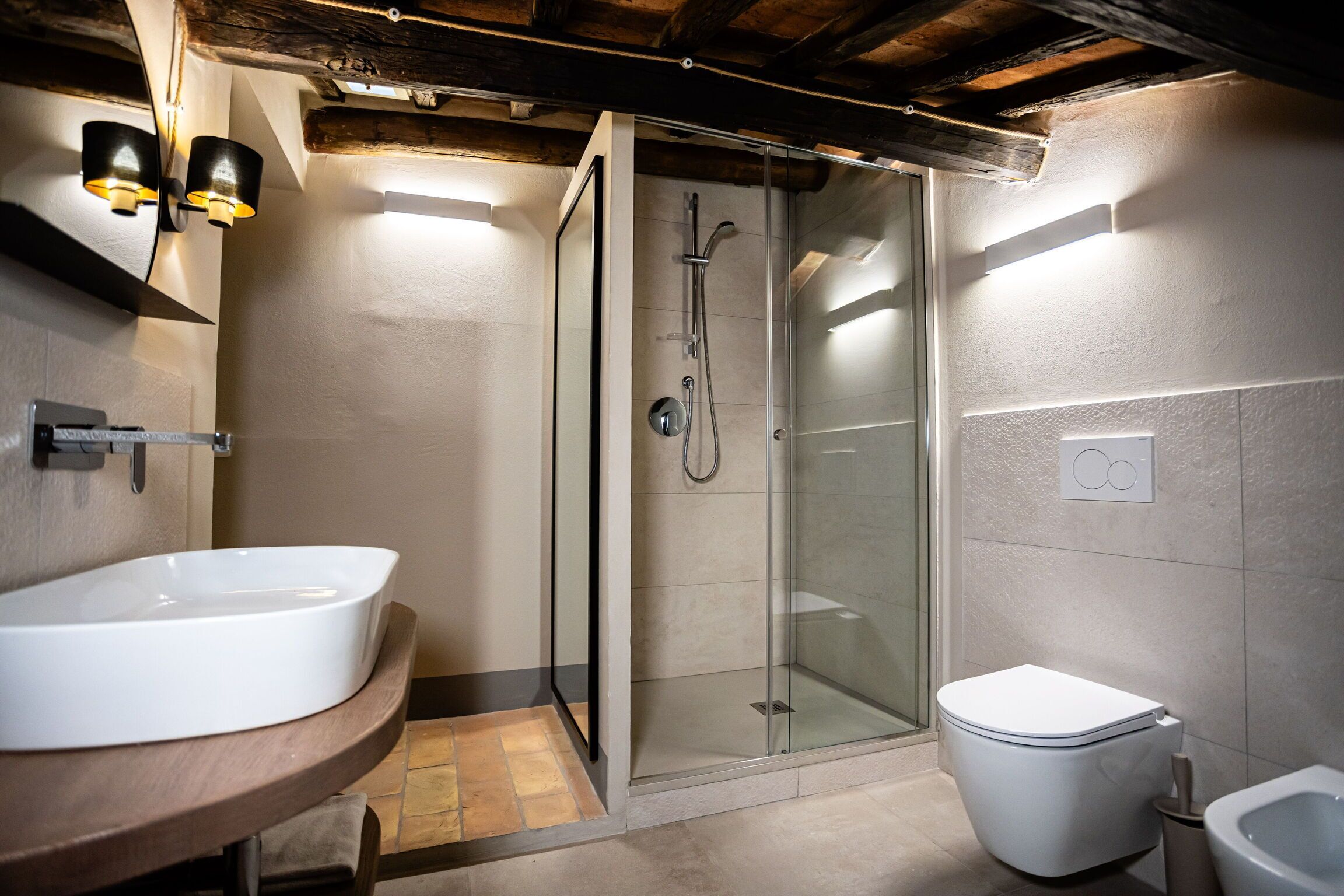 A bathroom with a glass-enclosed shower, a white sink, and a toilet.