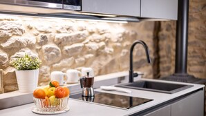 Eine moderne Küche mit Steinwand, Spüle, Kaffeemaschine und Obstschale.