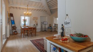 A spacious kitchen with wooden flooring, a chandelier, a dining area with a table and chairs, and a sign that reads 'Live Simply.' - La Terrazza Sulla Valle (Cortona)