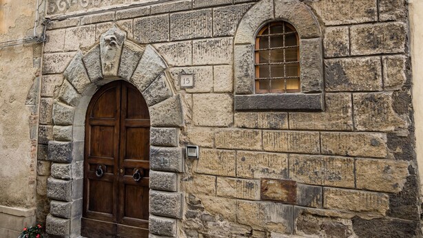 A stone building with a wooden door and a window. - Rose's Palace (Cortona)