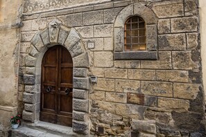 A stone building with a wooden door and a window. - Rose's Palace (Cortona)