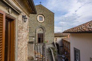 A narrow street with a stone building featuring a wooden door and a small window. - Rose's Palace (Cortona)