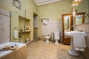 A bathroom with a bathtub, two toilets, a sink, a mirror, and a shower. - Rose's Palace (Cortona)