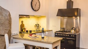 A kitchen with a stove, oven, and a clock on the wall. - Rose's Palace (Cortona)