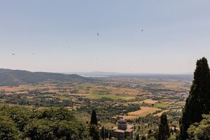 Une vue panoramique d’un paysage avec un bâtiment imposant doté d’un dôme, entouré de collines et de champs vallonnés.