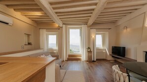 Uma sala de estar moderna com piso e teto de madeira, um sofá, uma mesa de jantar e uma televisão.