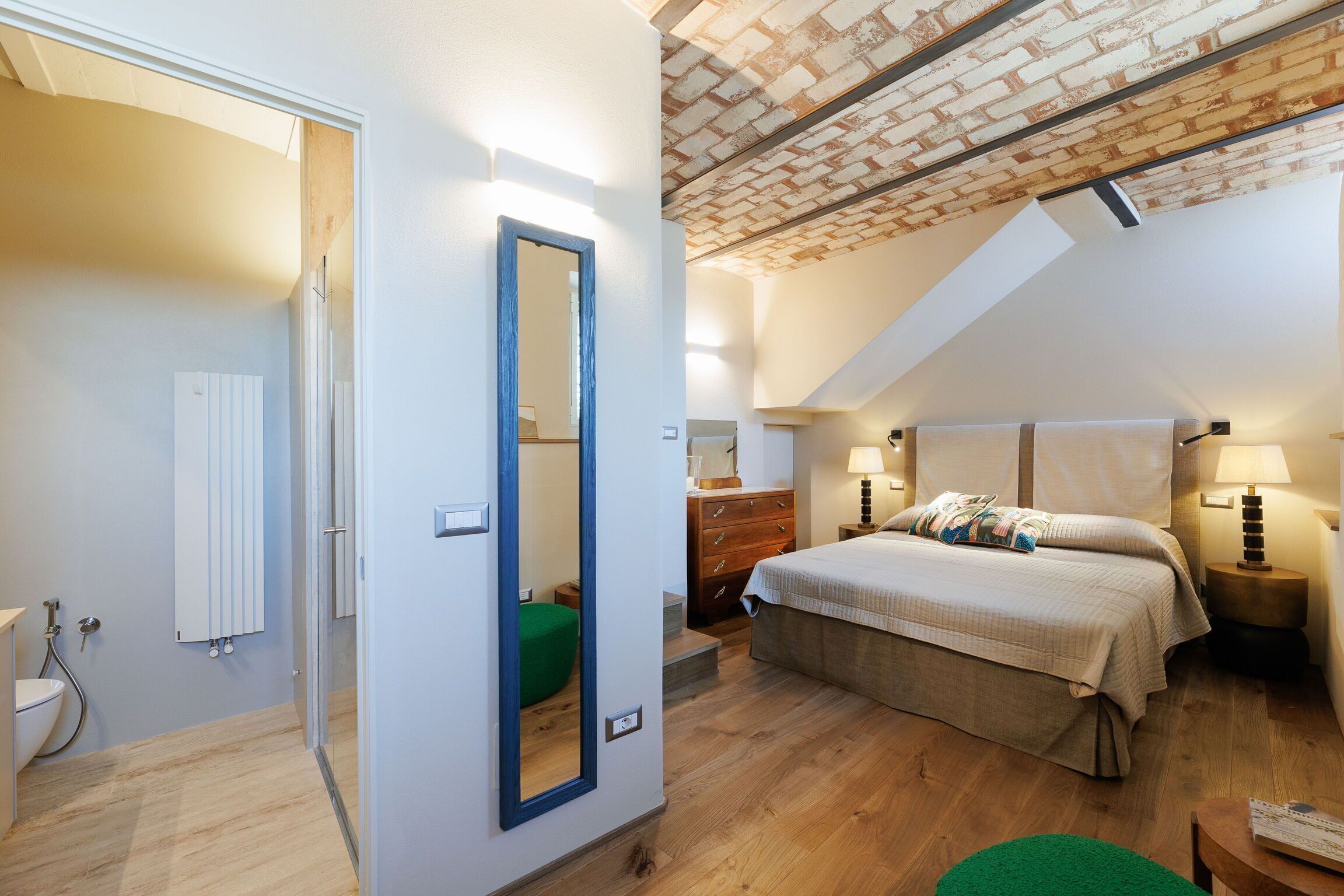 Un dormitorio con techo inclinado, una cama, un tocador y un espejo.