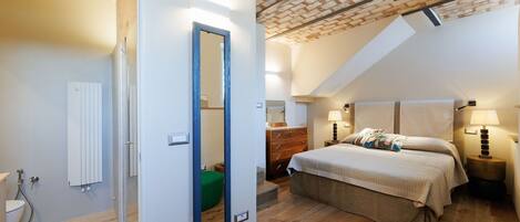 Un dormitorio con techo inclinado, una cama, un tocador y un espejo.
