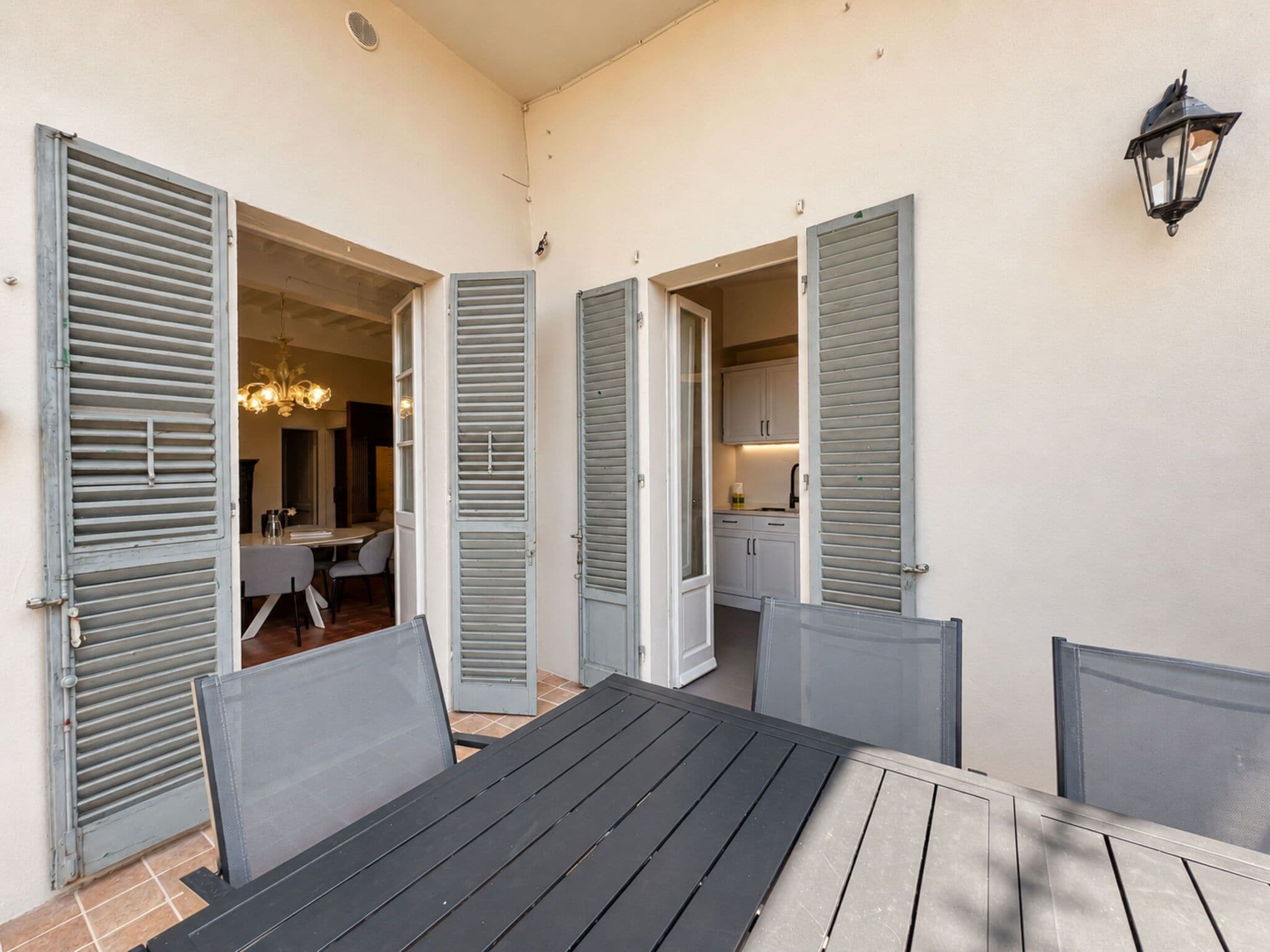 An outdoor dining area with a table and chairs, connected to a kitchen and dining room through open doors.