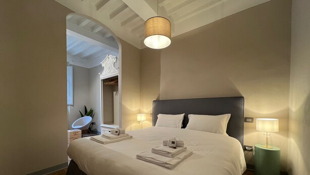 Un dormitorio con una cama grande, dos lámparas de noche, un espejo y una mesita de noche verde.