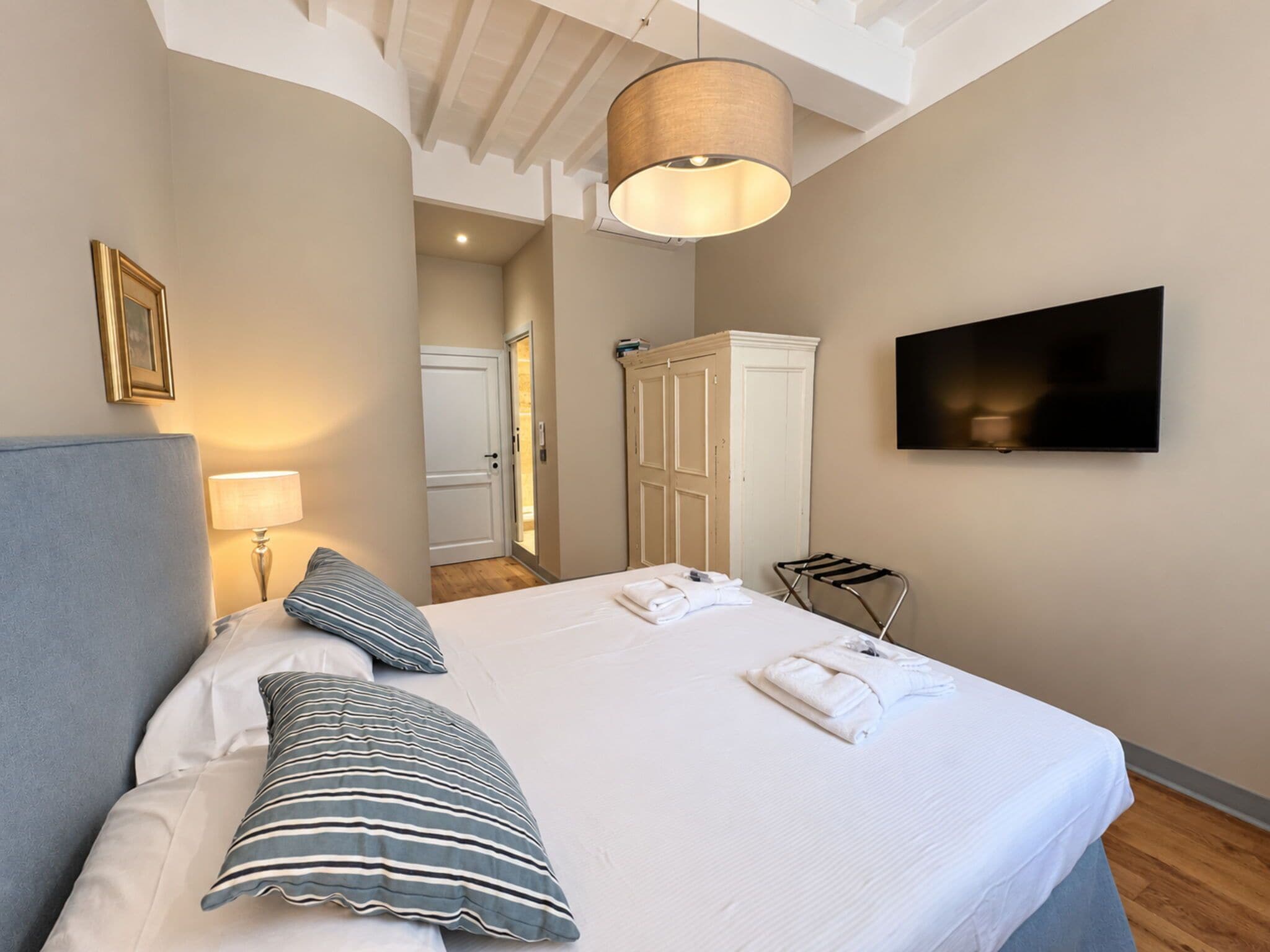 Ein Hotelzimmer mit einem Bett, einem Fernseher, einem Kleiderschrank und einem Badezimmer im Hintergrund.